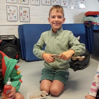 Child showing off a craft project made from an egg carton