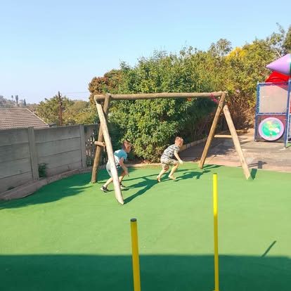 Children playing on grass with a jungle gym in the background