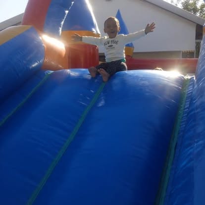 Child happily sliding down a blue inflatable bouncy castle