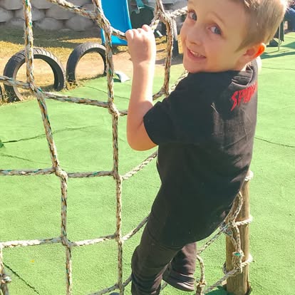 Child climbing a rope net structure outdoors