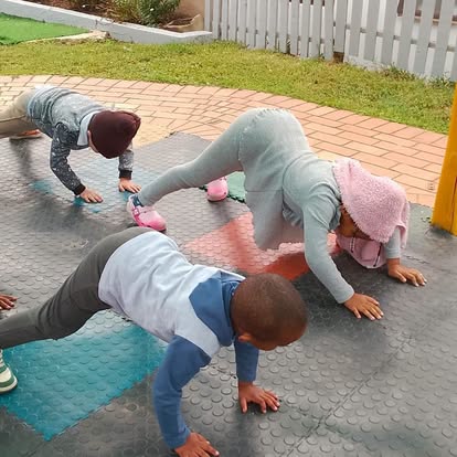 Children doing pushups on a padded outdoor mat