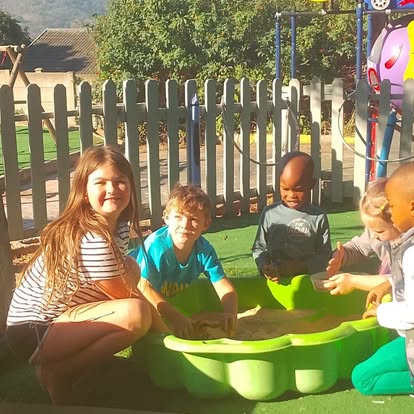 Children playing together in a green flower-shaped sandpit
