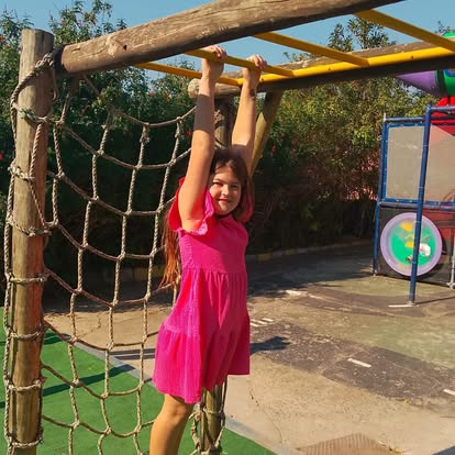 Child hanging from yellow monkey bars